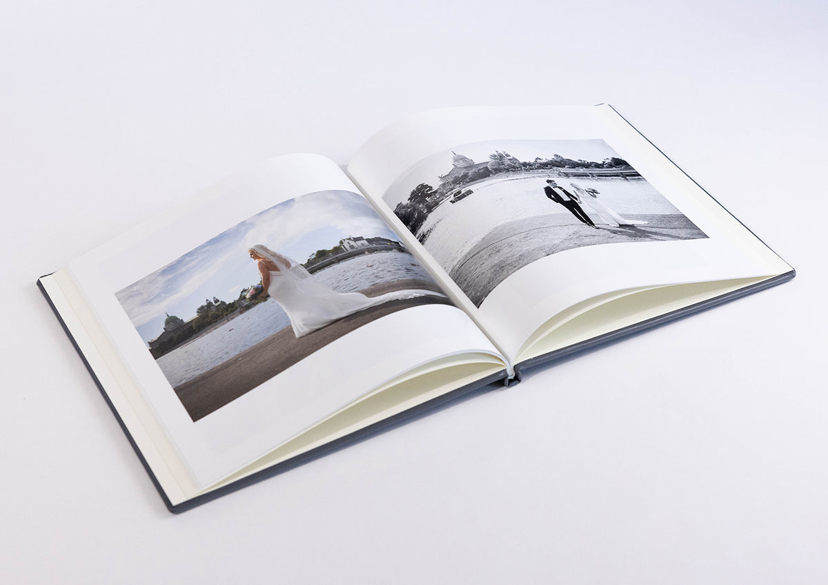 Stone Grey leatherette coffee table book open at a wedding photo spread of the bride and groom by the sea