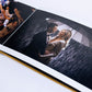 Open Dijon Yellow velvet wedding album showing lay-flat pages with a couple under an umbrella in the rain