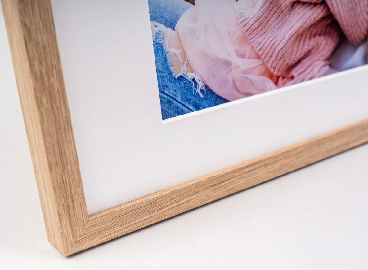 Close-up of a natural oak photo frame corner with a white mount