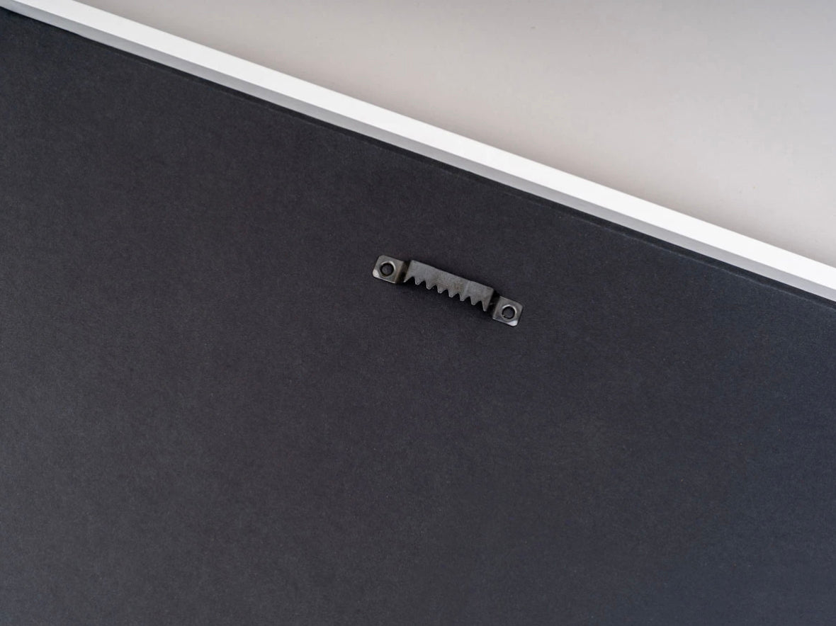 Back of a white photo frame showing the sawtooth hanger, ready to hang