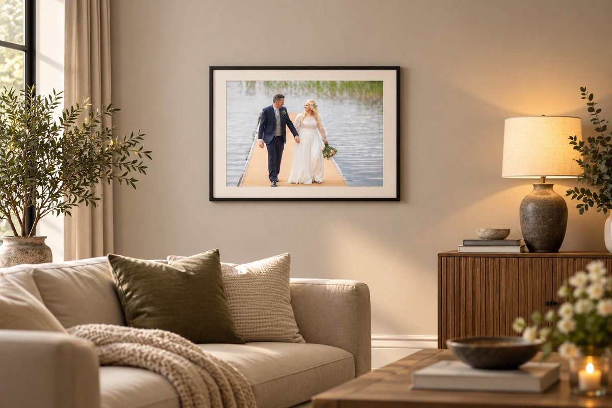 Framed wedding photo print in a black frame with a white mount, hanging in a living room