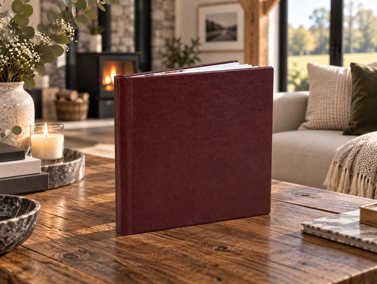 Burgundy leatherette wedding album standing on a rustic wooden coffee table in a cosy living room