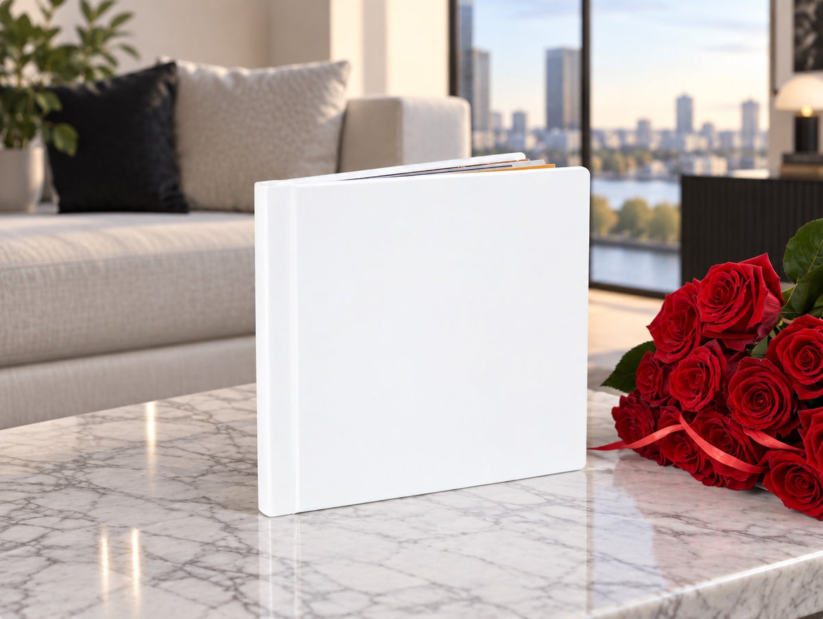 White leatherette wedding album on a marble coffee table with red roses