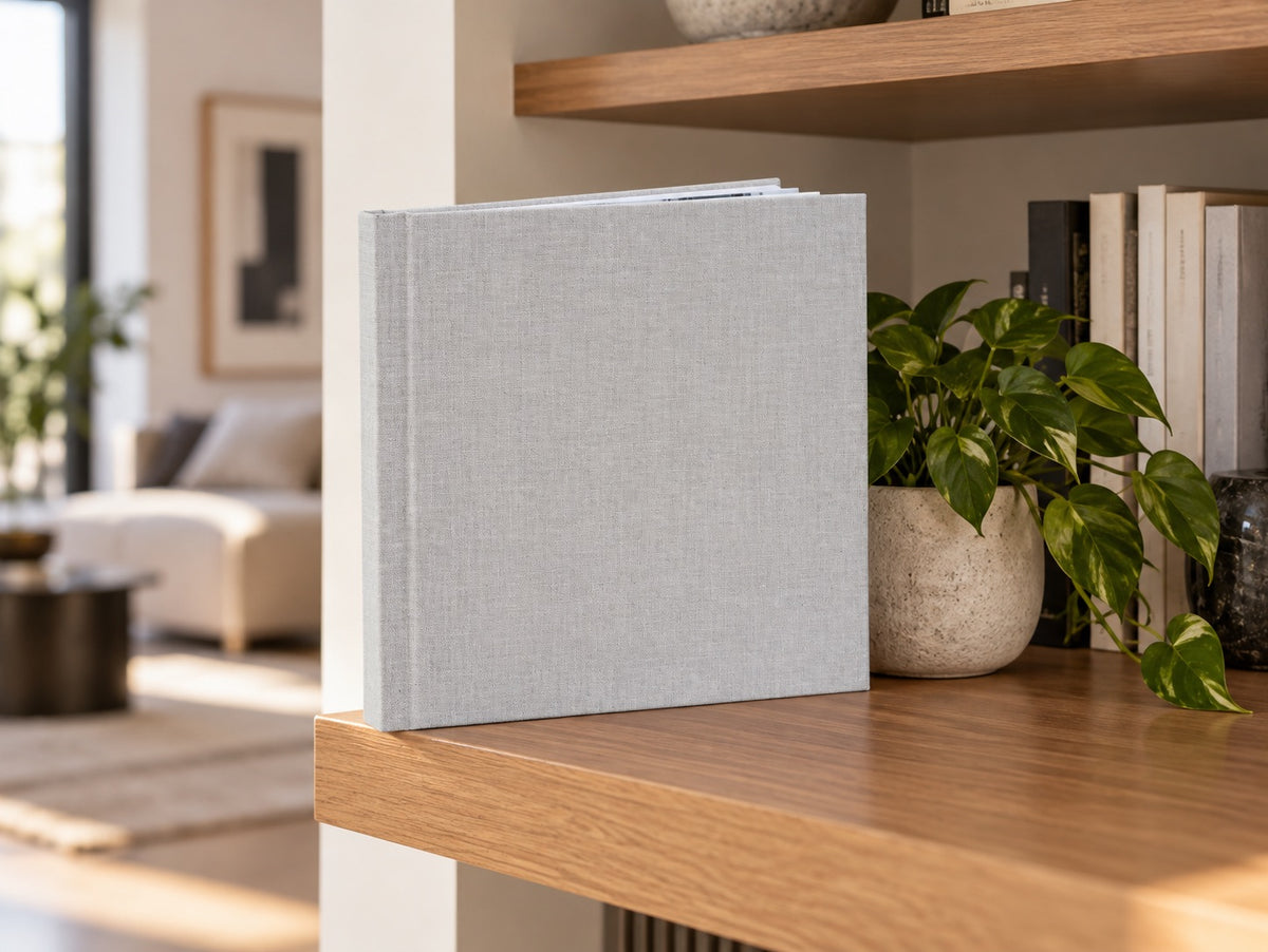 Mist Grey linen wedding album standing on a wooden shelf in a bright living room